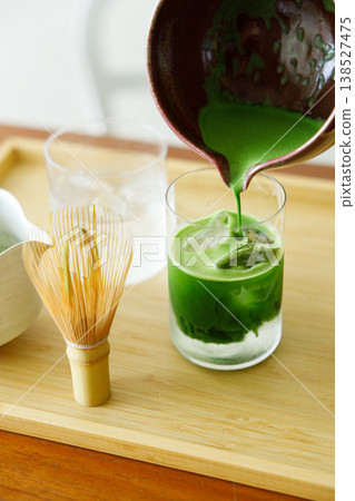 fresh matcha tea, green tea pouring on a glass of coconut water on white wooden table. fresh matcha tea, green tea pouring on a glass of coconut water on white wooden table. 138527475