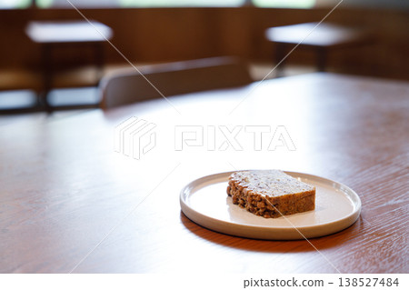 a piece of banana bread cake on table by the window. a piece of banana bread cake on table by the window. 138527484