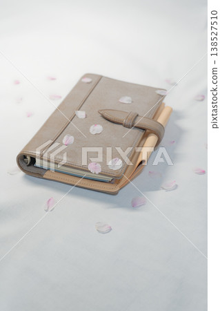 Cherry blossom petals and a notebook: A new life image with plenty of blank space. Cherry blossom petals and a notebook: A new life image with plenty of blank space. 138527510