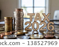 Stacked coins and wooden letters spelling TAX 2026 on table with blurred background 138527969