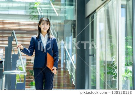 A young woman in a suit walking through the entrance of an office building. A young woman in a suit walking through the entrance of an office building. 138528158