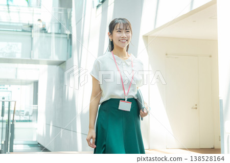 A young woman walking down the hallway with her notebook in her hand. 138528164