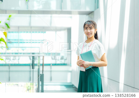 A young woman walking down the hallway with her notebook in her hand. A young woman walking down the hallway with her notebook in her hand. 138528166
