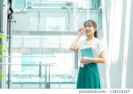 A young woman walking down the hallway with her notebook in her hand. A young woman walking down the hallway with her notebook in her hand. 138528167