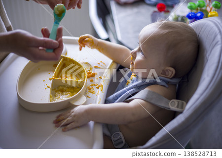 Child Refuses Spoon. Infant Playfully Defies Feeding. Baby Mockingly Challenges During Meal Time. Humorous Scene Where Young Child Resists Spoon During Mealtime Child Refuses Spoon. Infant Playfully Defies Feeding. Baby Mockingly Challenges During Meal Time. Humorous Scene Where Young Child Resists Spoon During Mealtime 138528713