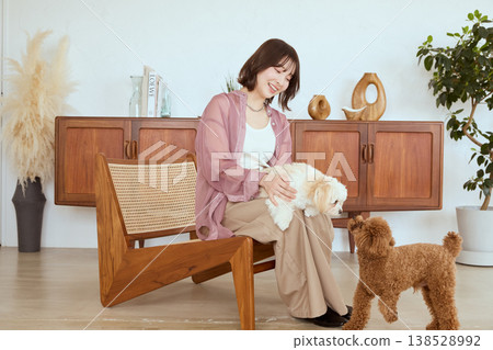 A woman living with a Maltese and a Toy Poodle: Life in a living room with multiple pets. A woman living with a Maltese and a Toy Poodle: Life in a living room with multiple pets. 138528992
