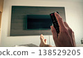 First person view of a man relaxing in hotel bed with remote control facing television. Turning on TV 138529205