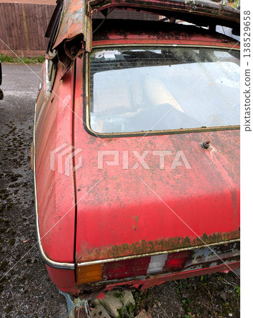 A rusted vintage car being abandoned on a street with flat tires and rusty bodywork 138529658