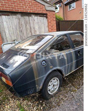 A rusted vintage car being abandoned on a street with flat tires and rusty bodywork 138529662