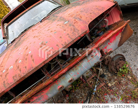 A rusted vintage car being abandoned on a street with flat tires and rusty bodywork 138529676