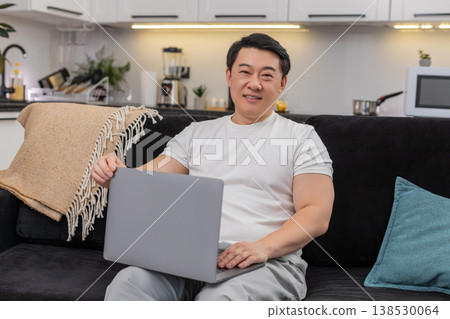 Asian man opens laptop starts work boots system types fast smiles with confidence and begins strong 138530064