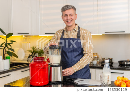 Middle-aged man making protein shake in kitchen blender for fitness breakfast and healthy nutrition Middle-aged man making protein shake in kitchen blender for fitness breakfast and healthy nutrition 138530129