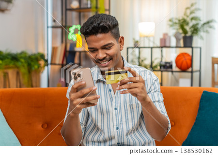 Indian man shops online with smartphone and card enters cvv confirms order success smiles delivery Indian man shops online with smartphone and card enters cvv confirms order success smiles delivery 138530162