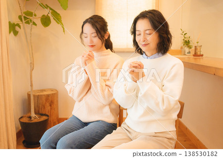 A mother and daughter pray for the deceased at home. A mother and daughter pray for the deceased at home. 138530182