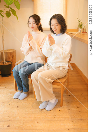 A mother and daughter pray for the deceased at home. A mother and daughter pray for the deceased at home. 138530192