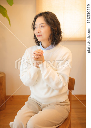 A middle-aged woman praying for the deceased at home A middle-aged woman praying for the deceased at home 138530259