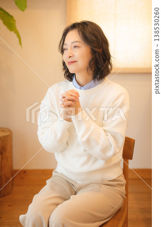 A middle-aged woman praying for the deceased at home A middle-aged woman praying for the deceased at home 138530260