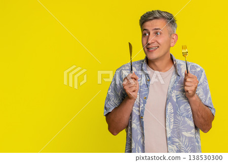 Man holding knife and fork looking at camera with hungry expression waiting for tasty delicious food 138530300