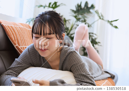 一位女士正在客廳裡享受她的智慧型手機；輕鬆愜意的生活方式。 138530518