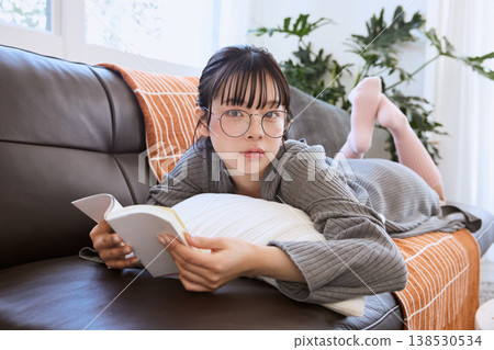 一位戴眼鏡的女士正在看書；在家中享受輕鬆的閱讀時光。 138530534