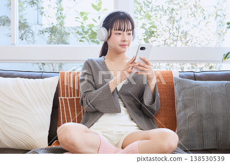 A woman using her smartphone with headphones: A lifestyle enjoyed at home A woman using her smartphone with headphones: A lifestyle enjoyed at home 138530539