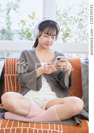 一位女士戴著耳機使用智慧型手機：一種居家生活方式 138530541