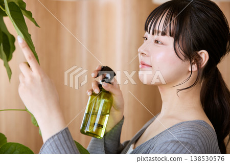 一位年輕女子用噴霧瓶為盆栽植物澆水。 138530576