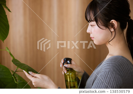 A young woman tending to houseplants 138530579