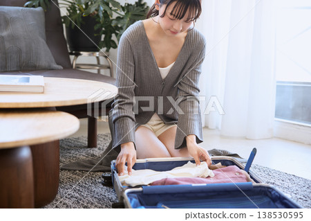 A young woman packs clothes into a suitcase in preparation for a trip. A young woman packs clothes into a suitcase in preparation for a trip. 138530595