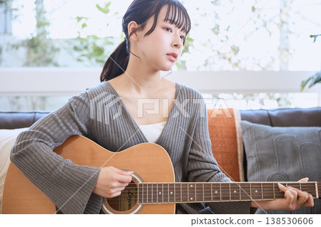 A young woman playing an acoustic guitar at home A young woman playing an acoustic guitar at home 138530606
