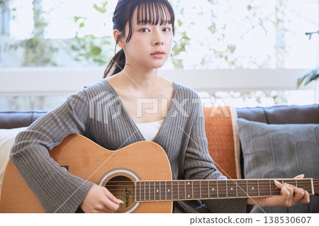 A young woman playing an acoustic guitar at home A young woman playing an acoustic guitar at home 138530607