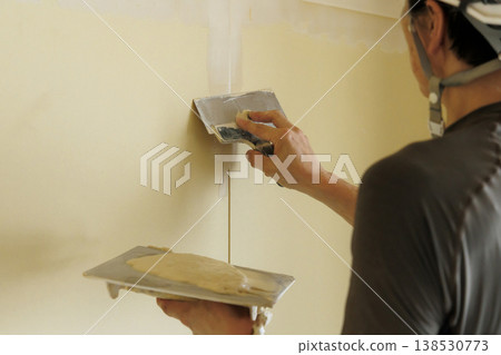 工匠正在用手將石膏塗抹在牆上。這是室內施工和翻新前進行表面處理的圖片。 138530773