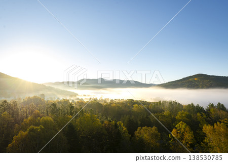 A breathtaking view of autumn leaves shining in the morning sun and a fantastical sea of clouds: A magnificent natural landscape of Hokkaido in autumn. A breathtaking view of autumn leaves shining in the morning sun and a fantastical sea of clouds: A magnificent natural landscape of Hokkaido in autumn. 138530785