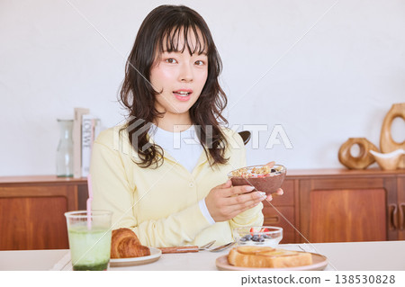 A young woman enjoying a healthy breakfast scene of an acai bowl. A young woman enjoying a healthy breakfast scene of an acai bowl. 138530828