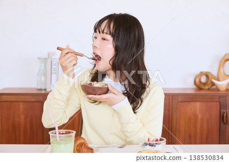A young woman eating an acai bowl for breakfast. A young woman eating an acai bowl for breakfast. 138530834