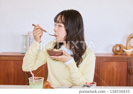 A young woman eating an acai bowl for breakfast. A young woman eating an acai bowl for breakfast. 138530835