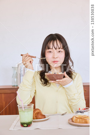 A young woman enjoying a healthy breakfast scene of an acai bowl. A young woman enjoying a healthy breakfast scene of an acai bowl. 138530838