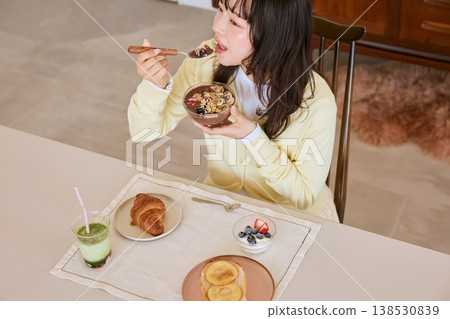 A young woman enjoying a healthy breakfast scene of an acai bowl. A young woman enjoying a healthy breakfast scene of an acai bowl. 138530839