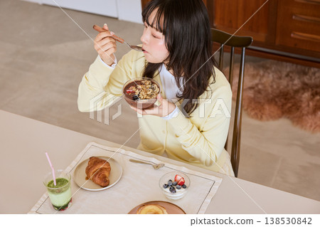 A young woman enjoying a healthy breakfast scene of an acai bowl. A young woman enjoying a healthy breakfast scene of an acai bowl. 138530842