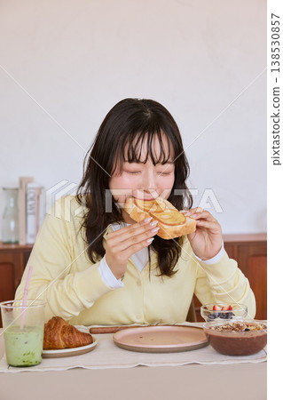 A young woman eating toast for breakfast at home. A young woman eating toast for breakfast at home. 138530857