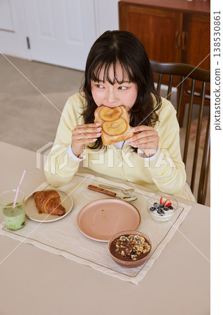 一位年輕女子在家吃早餐吐司。 138530861