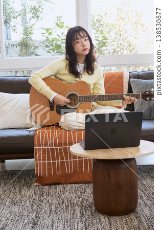 A woman practicing guitar online 138530877