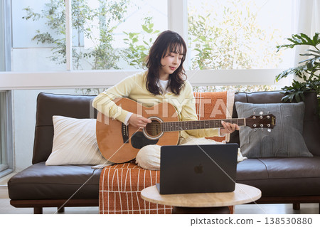 一位年輕女子在線練習吉他 一位年輕女子在線練習吉他 138530880
