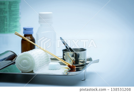 Wound care dressing set on stainless steel plate. Cotton ball with alcohol, cotton stick with povidone-iodine, forceps and conform bandage. Wound care dressing set on stainless steel plate. Cotton ball with alcohol, cotton stick with povidone-iodine, forceps and conform bandage. 138531208