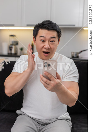 Asian man reads good news on smartphone eyes wide says wow smiles and shares positive update in chat Asian man reads good news on smartphone eyes wide says wow smiles and shares positive update in chat 138531273