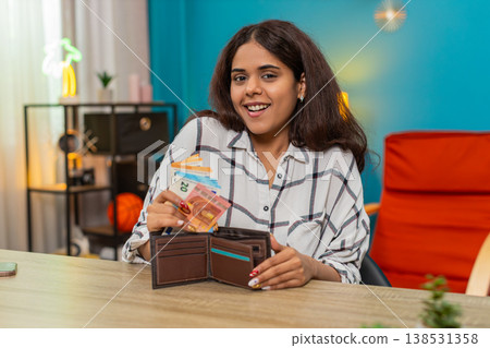 Indian rich woman counting euro cash placing bills into wallet feeling satisfied, proud wealth calm Indian rich woman counting euro cash placing bills into wallet feeling satisfied, proud wealth calm 138531358