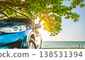 Blue sport SUV car parked by the tropical sea under umbrella tree. Summer vacation at the beach. Summer travel by car. Road trip. Automotive industry. Hybrid and electric car concept. Summer vibes. Blue sport SUV car parked by the tropical sea under umbrella tree. Summer vacation at the beach. Summer travel by car. Road trip. Automotive industry. Hybrid and electric car concept. Summer vibes. 138531394