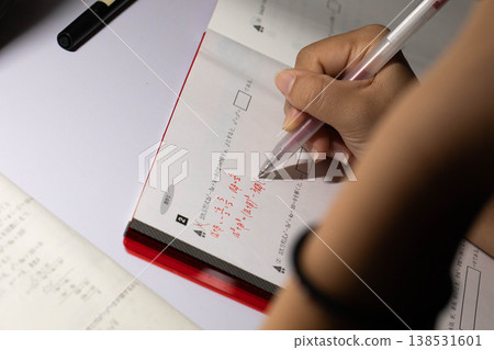 A high school student's hands working on a math problem; a scene of studying. 138531601
