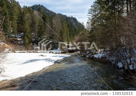Curving mountain stream with snow banks and forest in early spring Curving mountain stream with snow banks and forest in early spring 138532015