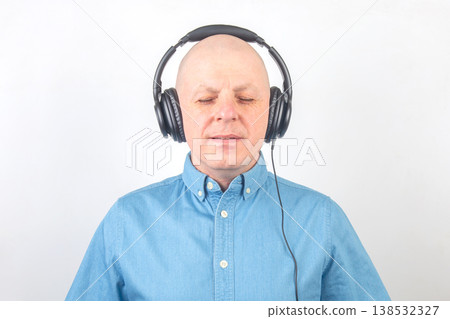Man listens to music while wearing headphones and enjoying a moment of relaxation in a simple Man listens to music while wearing headphones and enjoying a moment of relaxation in a simple 138532327